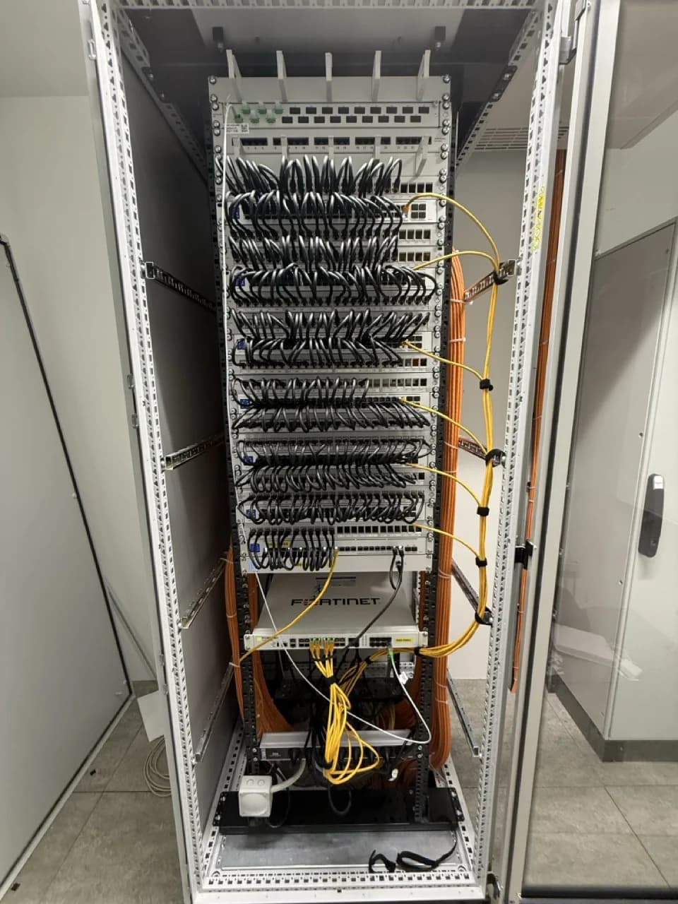 Netzwerk-Rack mit Patch-Panel, PoE-Switches und Fortinet-Firewall — strukturierte Verkabelung nach Installation